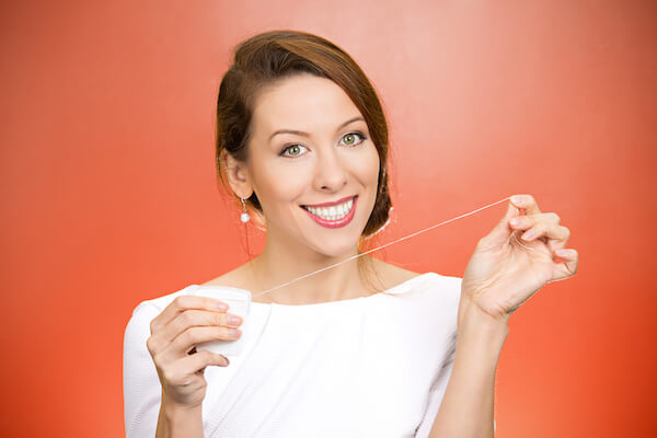 Closeup portrait, young pretty, beautiful, confident, smiling, cheerful female showing benefits of brushing flossing daily, isolated red background. Oral health, prevention of tooth decay