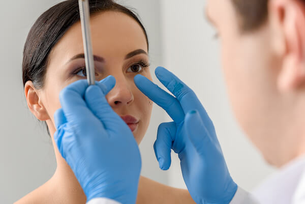 Focus on doctor hands showing where correct nose of calm woman. She watching at therapeutic