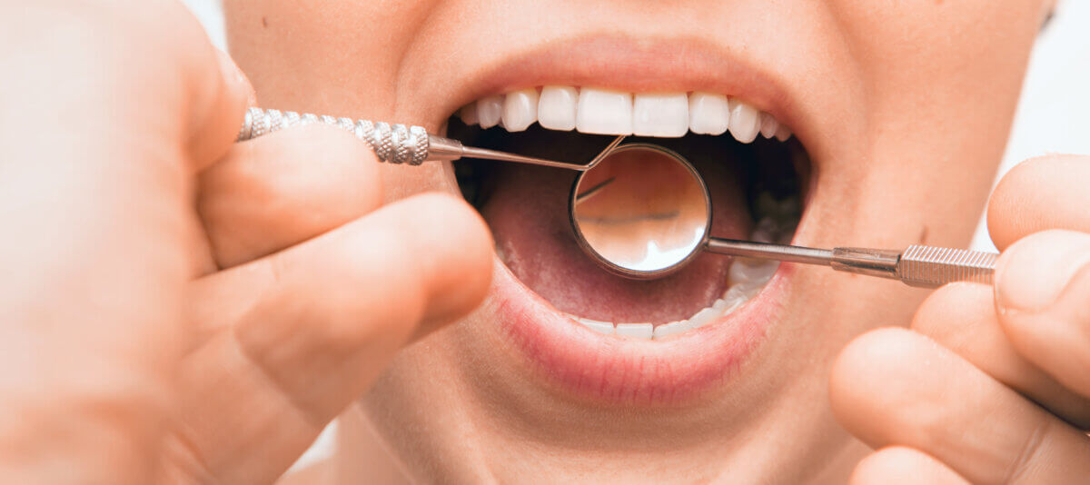 Doctor doing dental treatment to his patient in clinic. Teeth inspection and repair concept