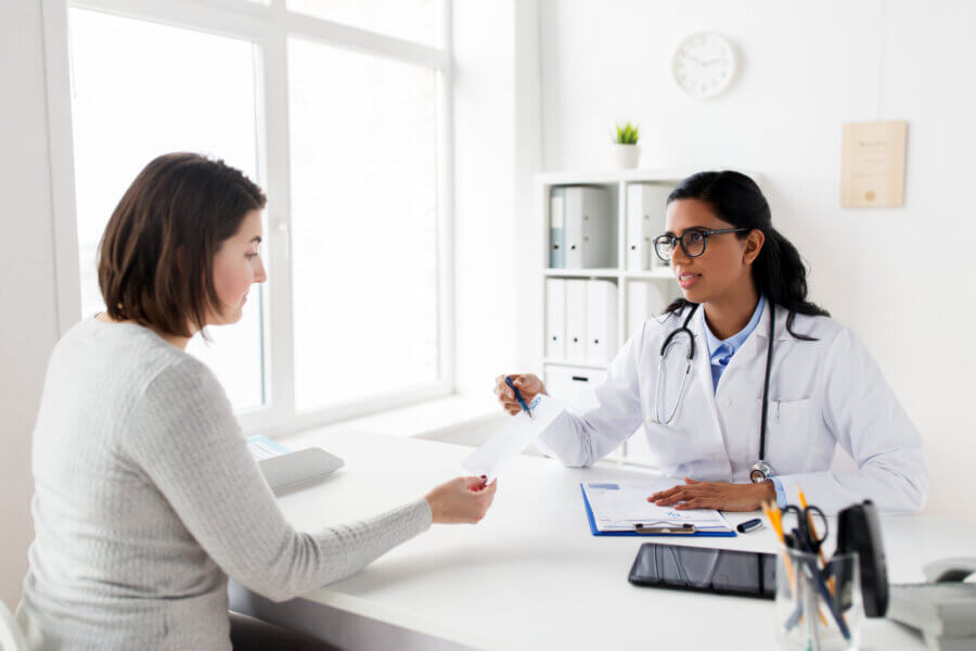 medicine, healthcare and people concept - doctor with clipboard and woman patient at hospital