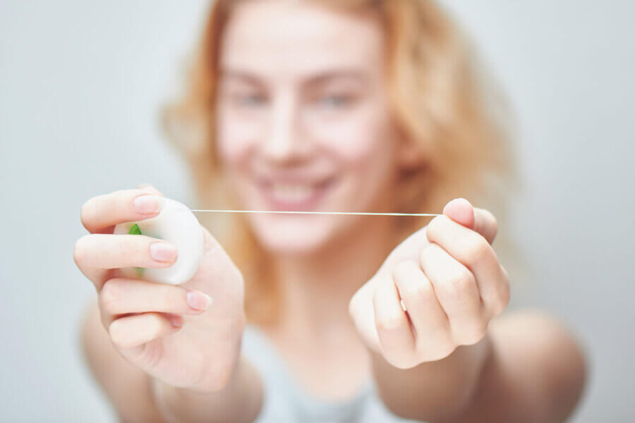 Girl holding out a floss piece, smiling. 