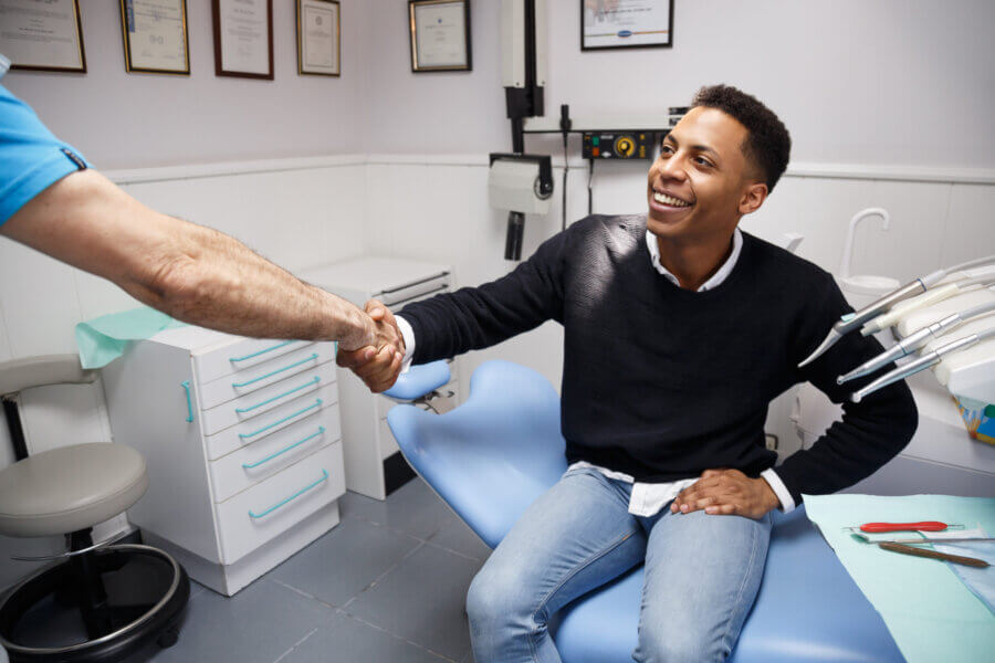 Young man in black shirt meeting dentist. Shaking hands with client and dentist. 