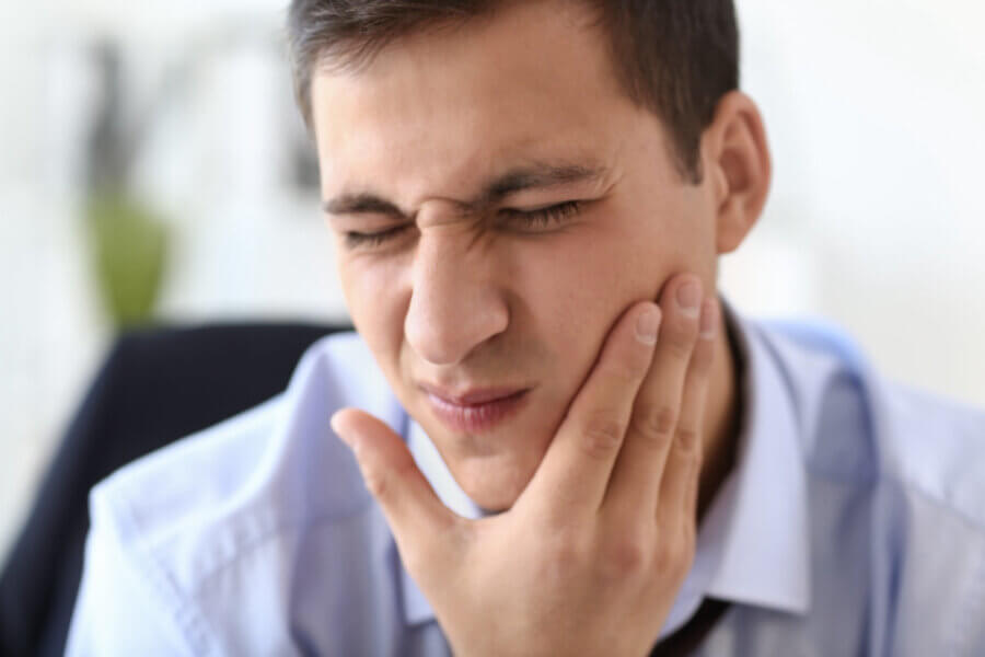 cracked tooth Young businessman suffering from toothache in office